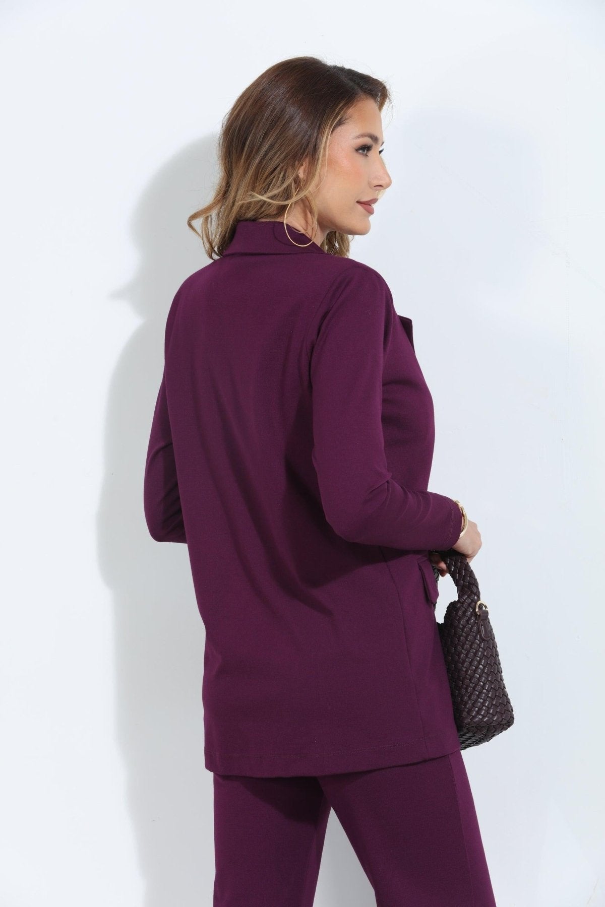 back side of dark purple blazer and pant set on woman holding deep purple purse