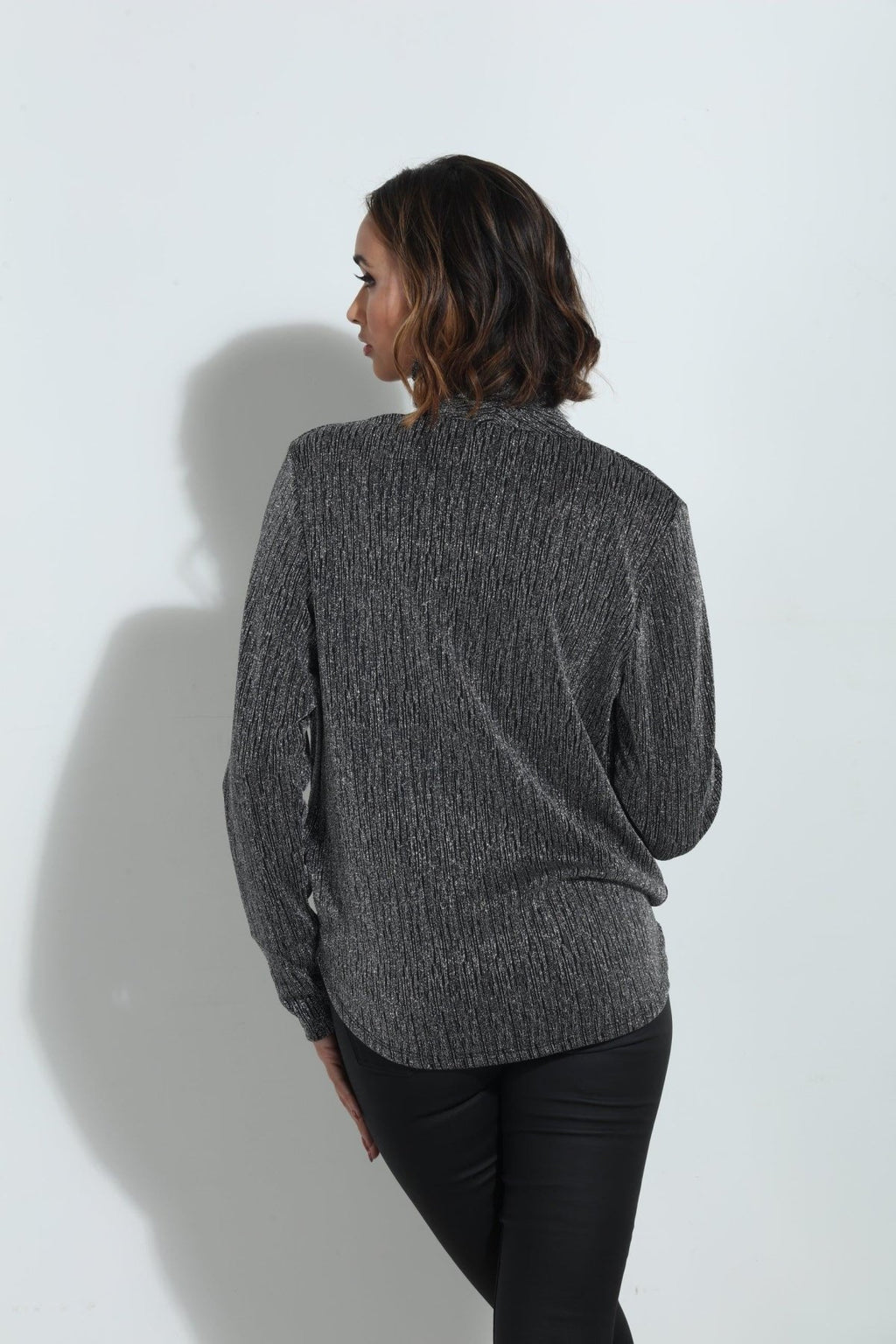 backside of silver and black long sleeve blouse on woman in black pants