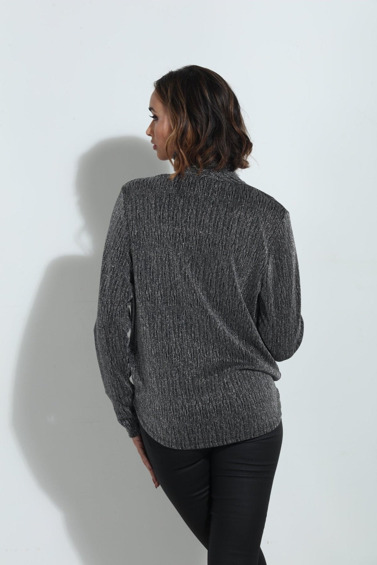 backside of silver and black long sleeve blouse on woman in black pants