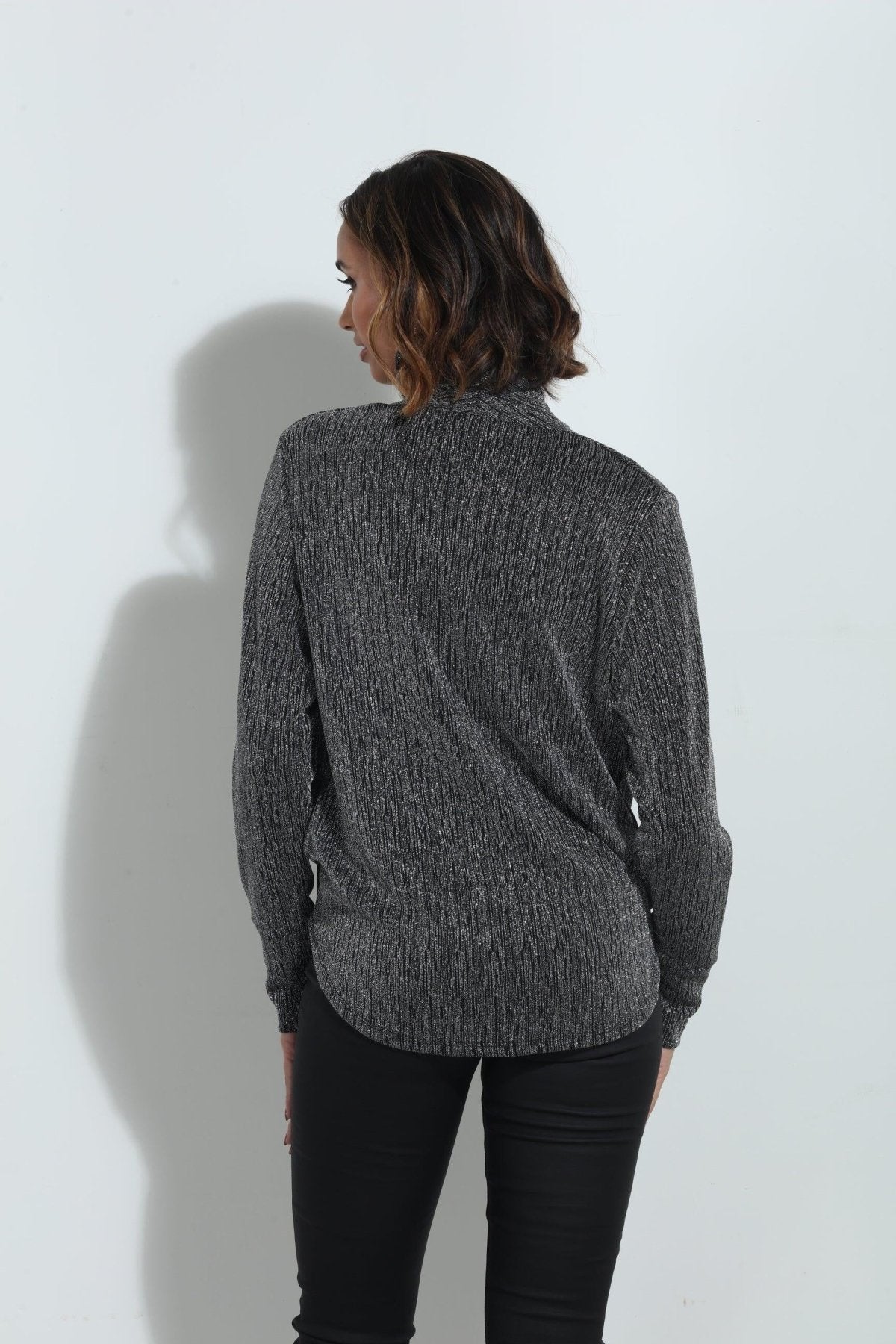 back side of silver and black long sleeve blouse on woman in black pants