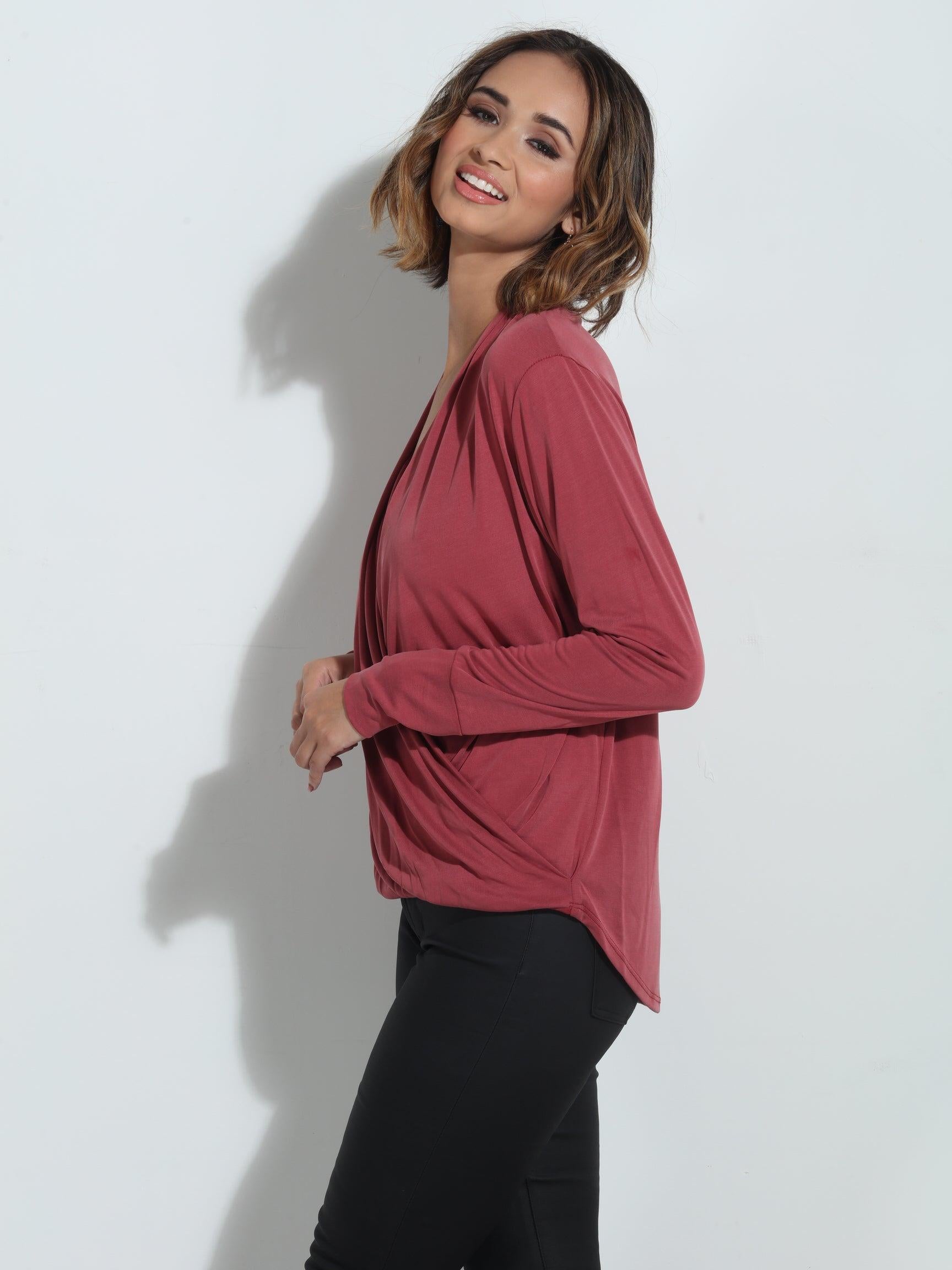 side angle of dark mauve long sleeve blouse on woman in dark denim pants