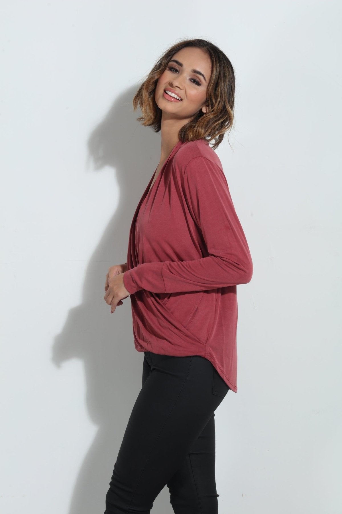 side angle of dark mauve long sleeve blouse on woman in dark denim pants