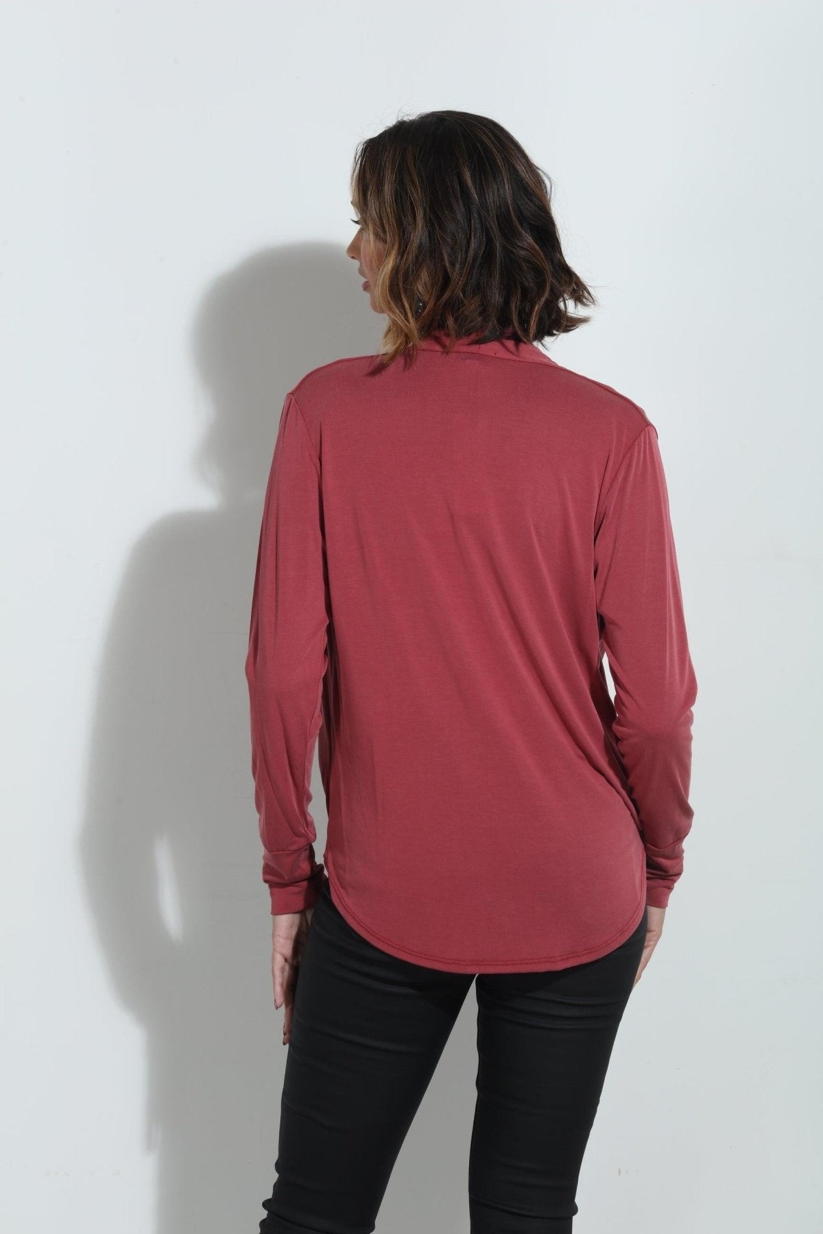 back side of dark mauve long sleeve blouse on woman in dark denim pants