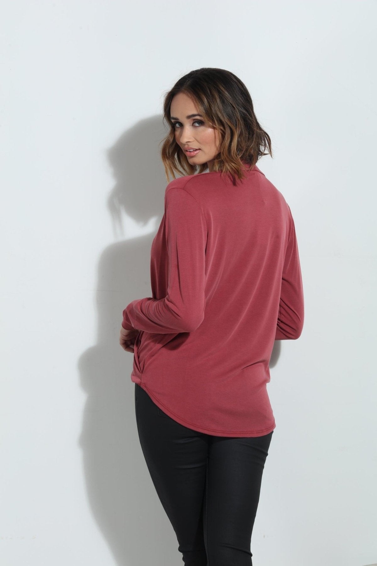 back side of dark mauve long sleeve blouse on woman in dark denim pants