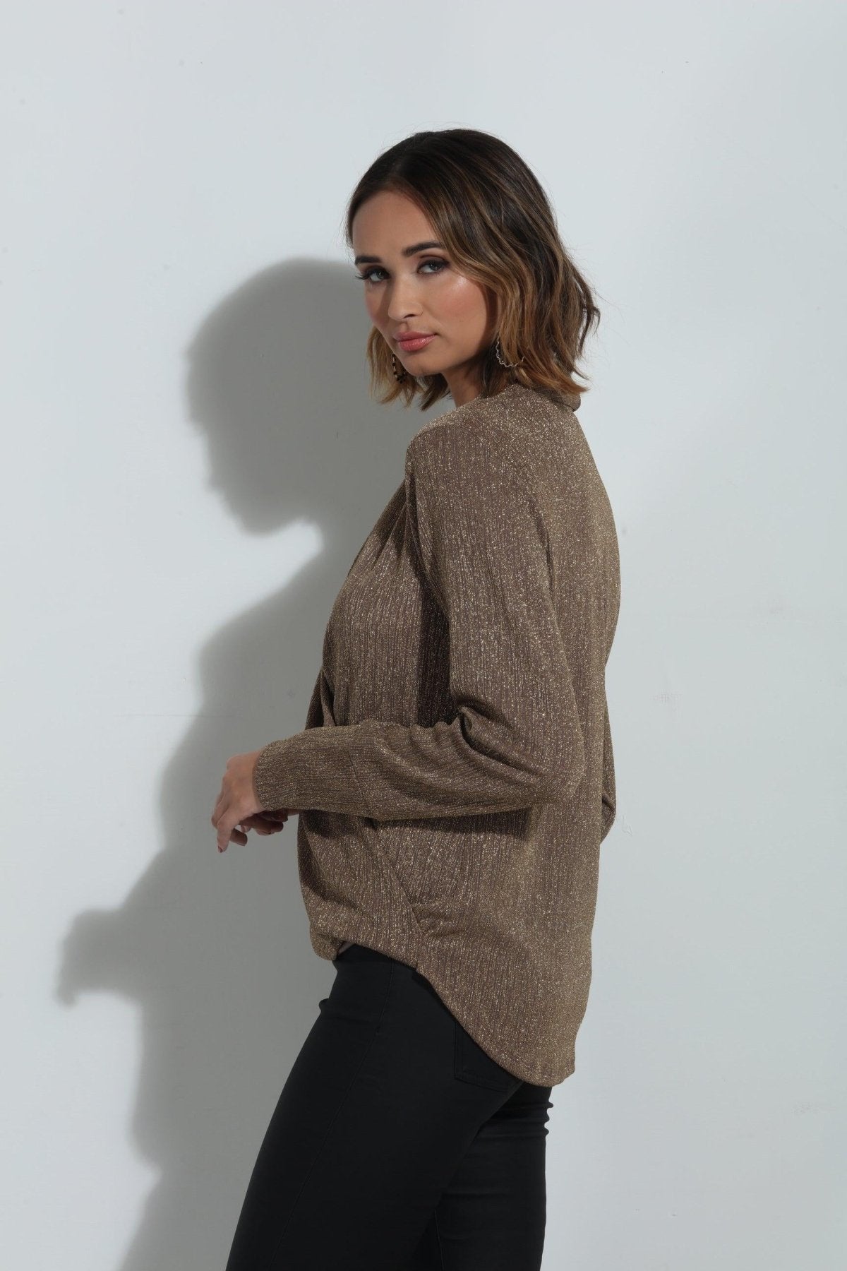 side angle of brown sparkle long sleeve blouse on woman in black pants