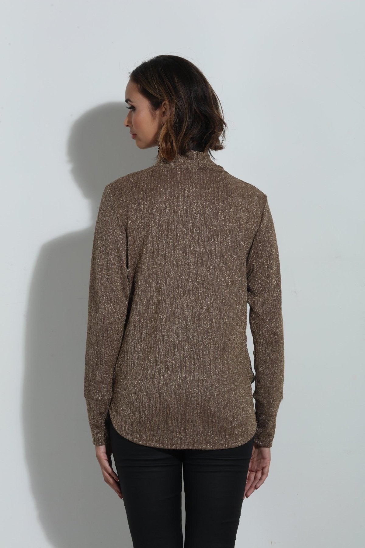back side of brown sparkle long sleeve blouse on woman in black pants