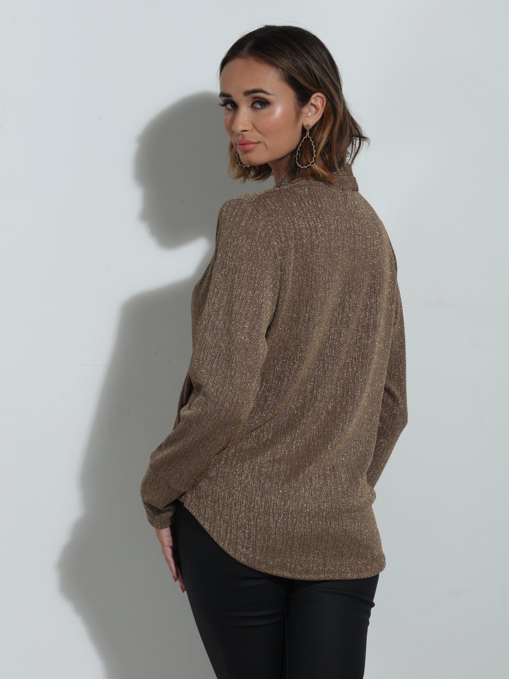 back side of brown sparkle long sleeve blouse on woman in black pants