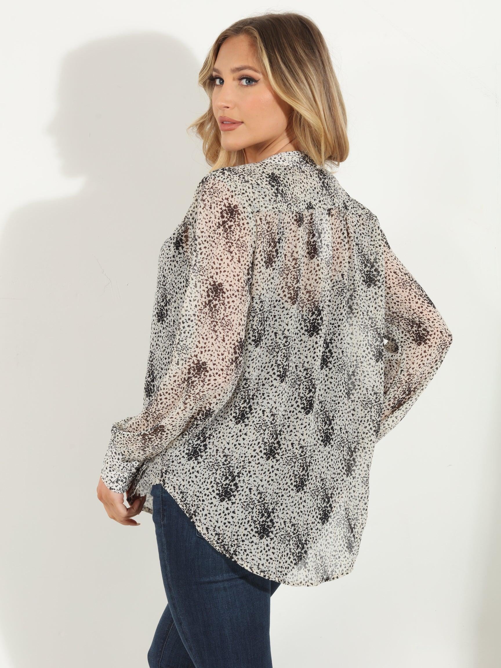 back side of white and black printed long sleeve blouse on woman in denim pants
