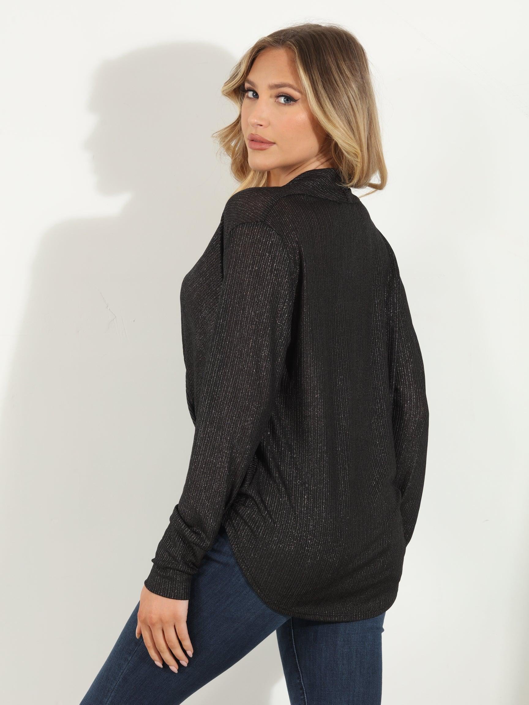backside of black and sparkle long sleeve blouse on woman in denim pants