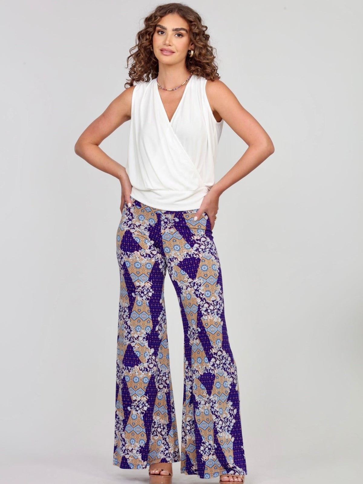 sleeveless white blouse and multicolored, printed pants on woman
