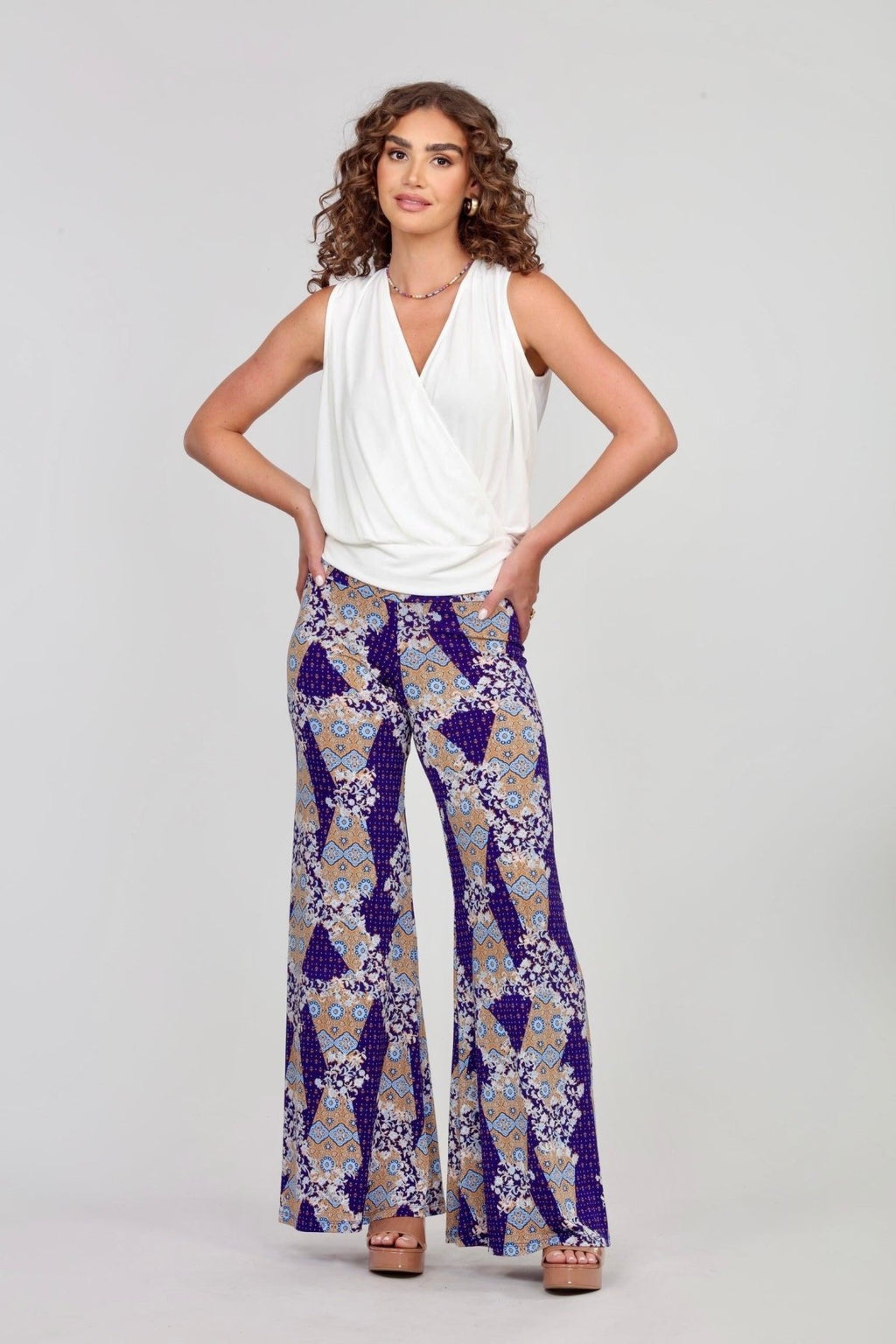 sleeveless white blouse and multicolored, printed pants on woman