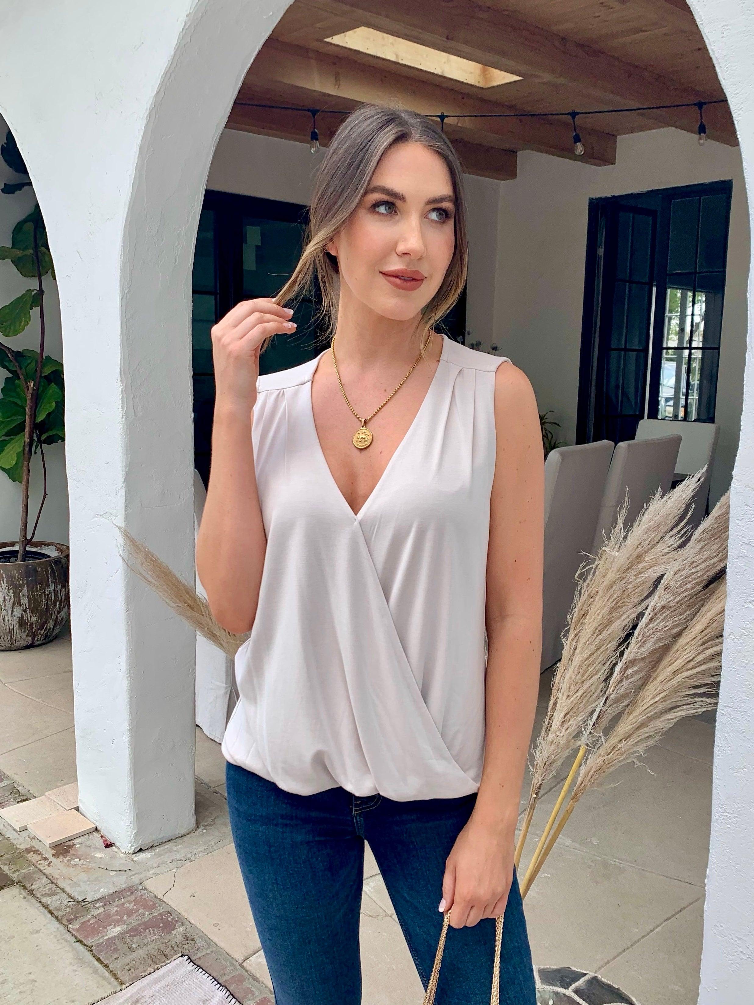 beige sleeveless blouse on woman in dark denim pants