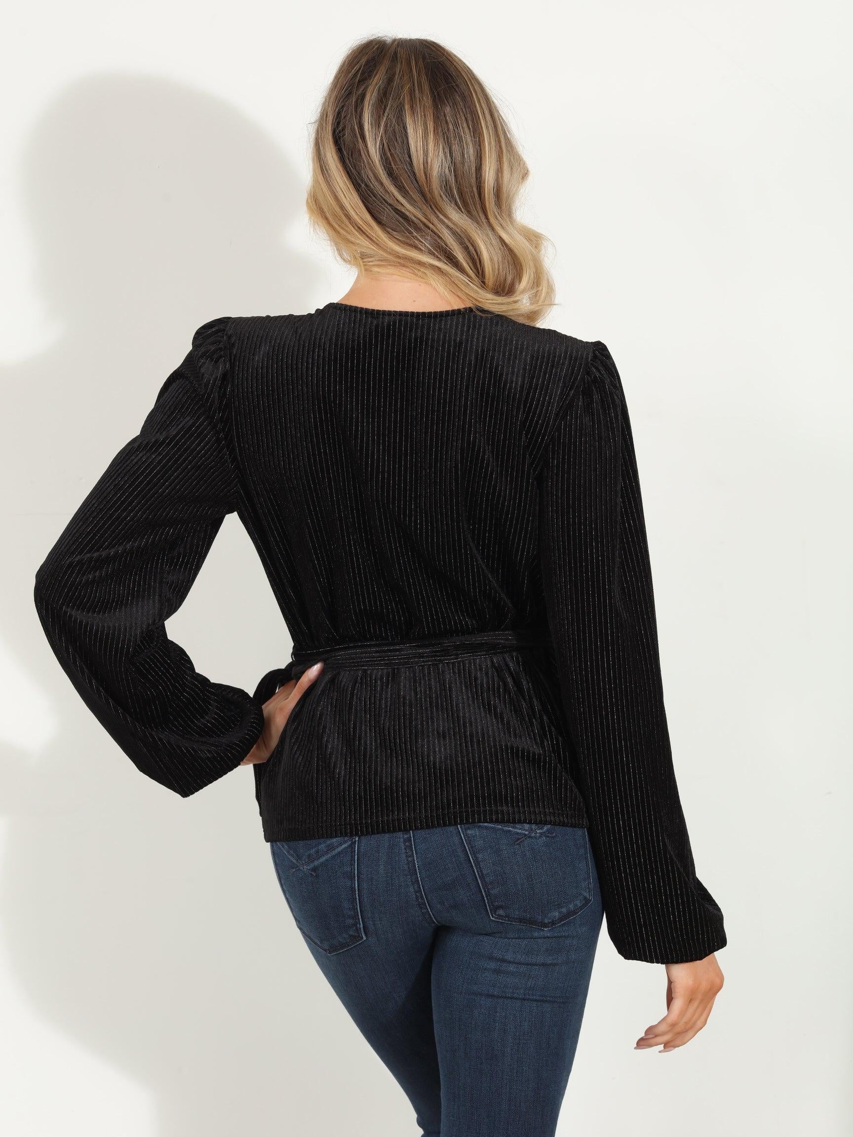 backside of woman in a black velvet wrap top and jeans