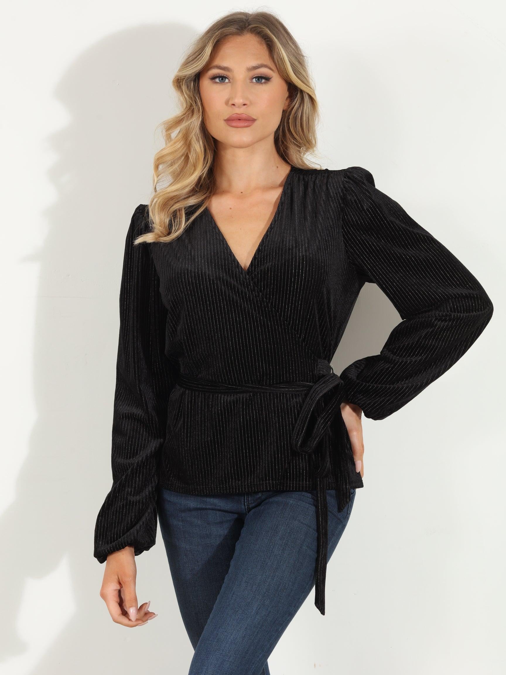woman in a black velvet wrap top and jeans