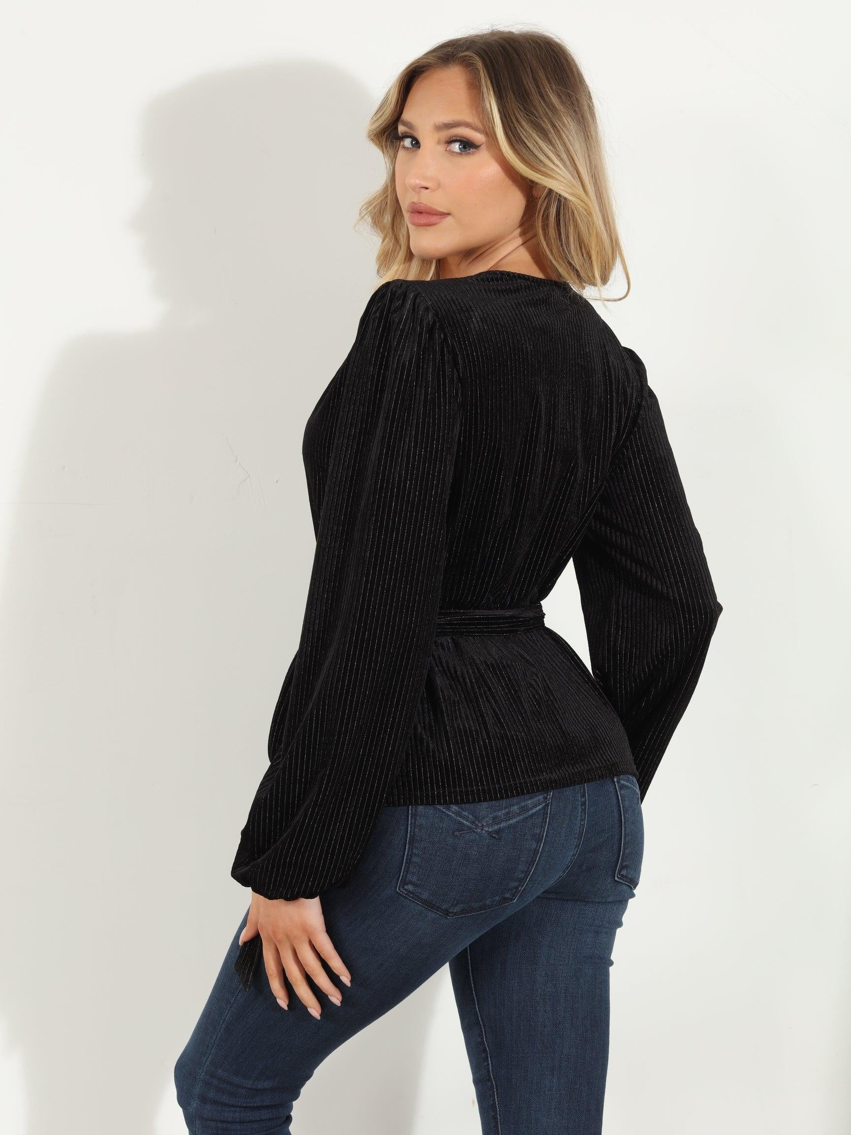 backside of woman in a black velvet wrap top and jeans