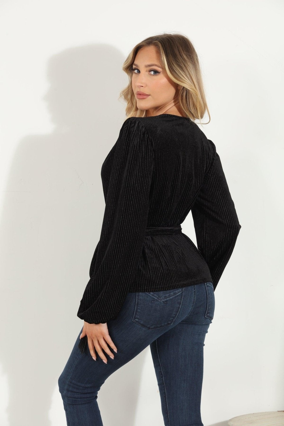 backside of woman in a black velvet wrap top and jeans