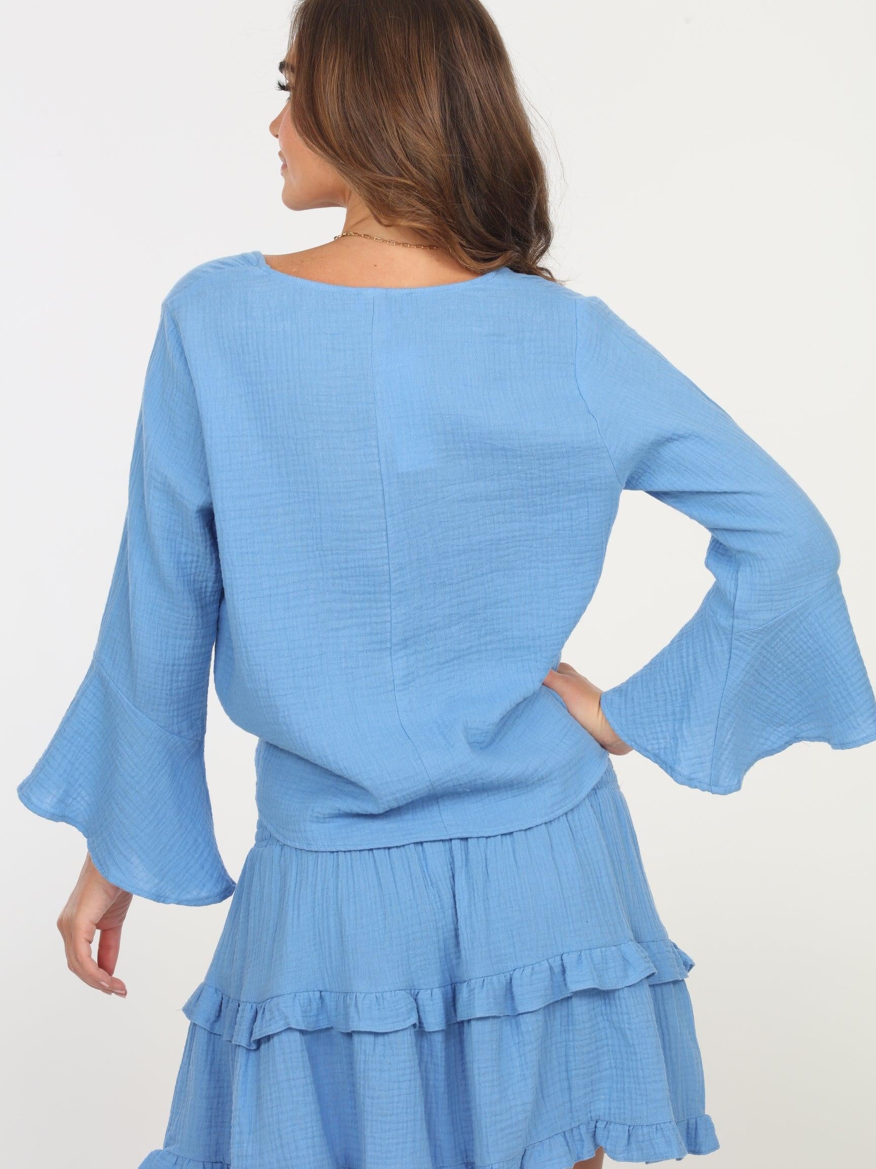 backside of woman in light blue long sleeve blouse and light blue skirt
