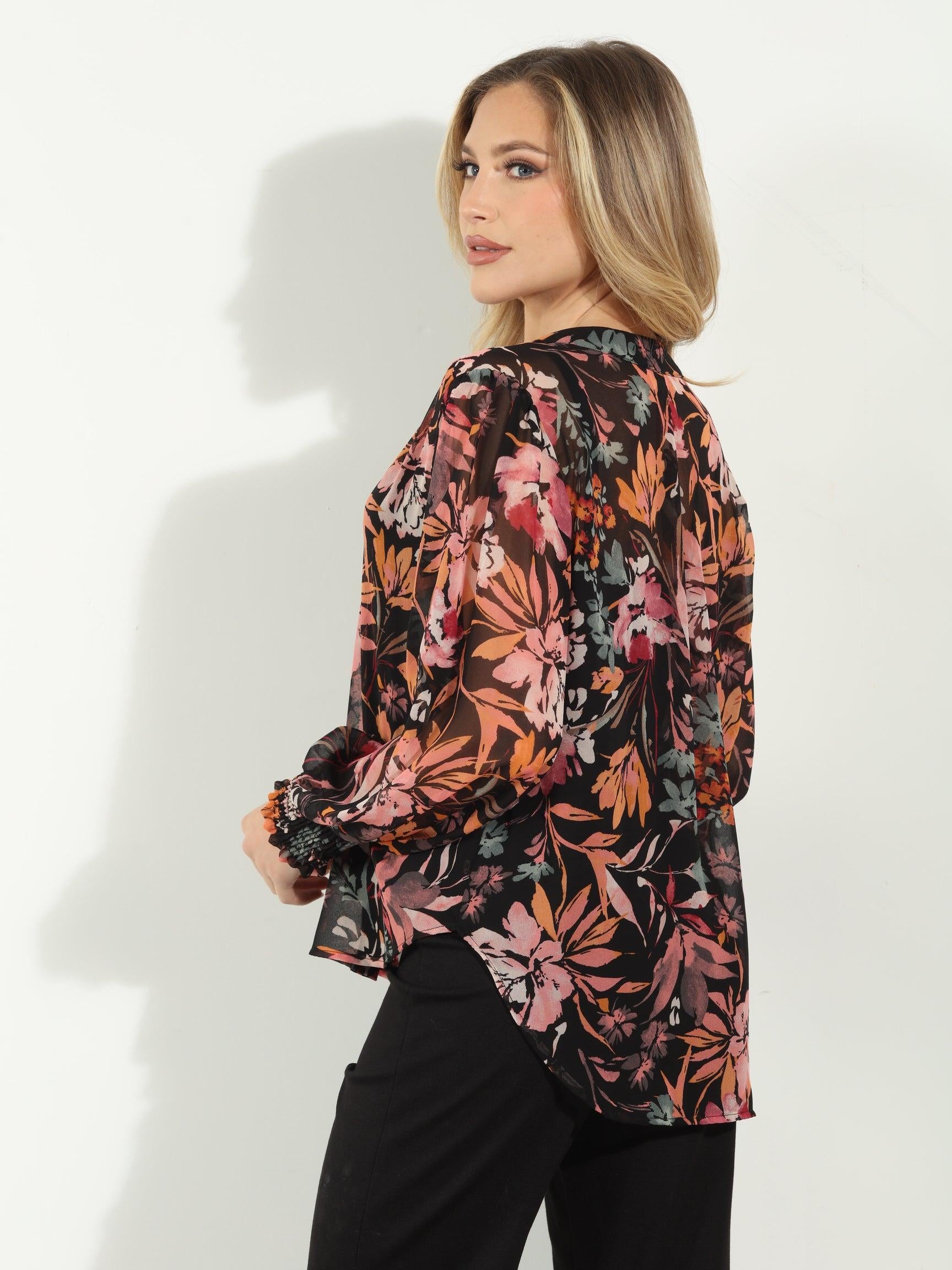 backside of multicolored long sleeve floral blouse on woman in black pants