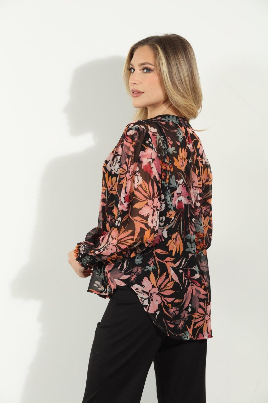 backside of multicolored long sleeve floral blouse on woman in black pants