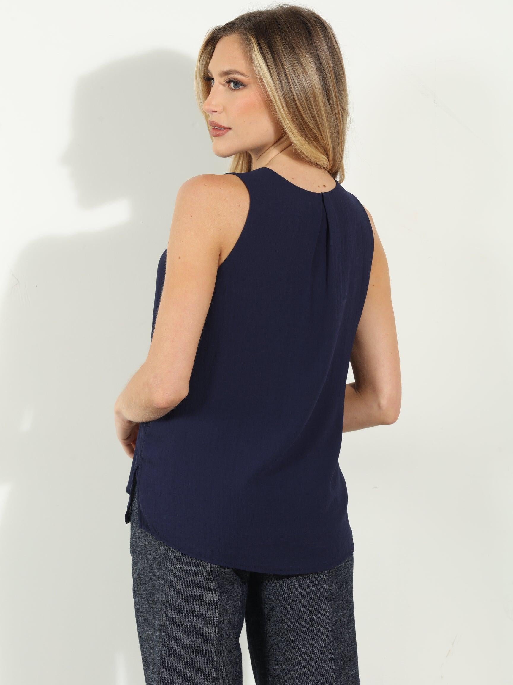 backside of navy sleeveless blouse on woman in denim pants