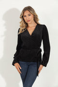 woman in a black velvet wrap top and jeans