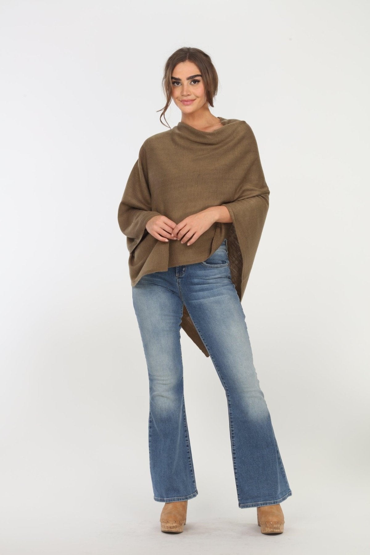 olive poncho on woman in denim pants and tan shoes