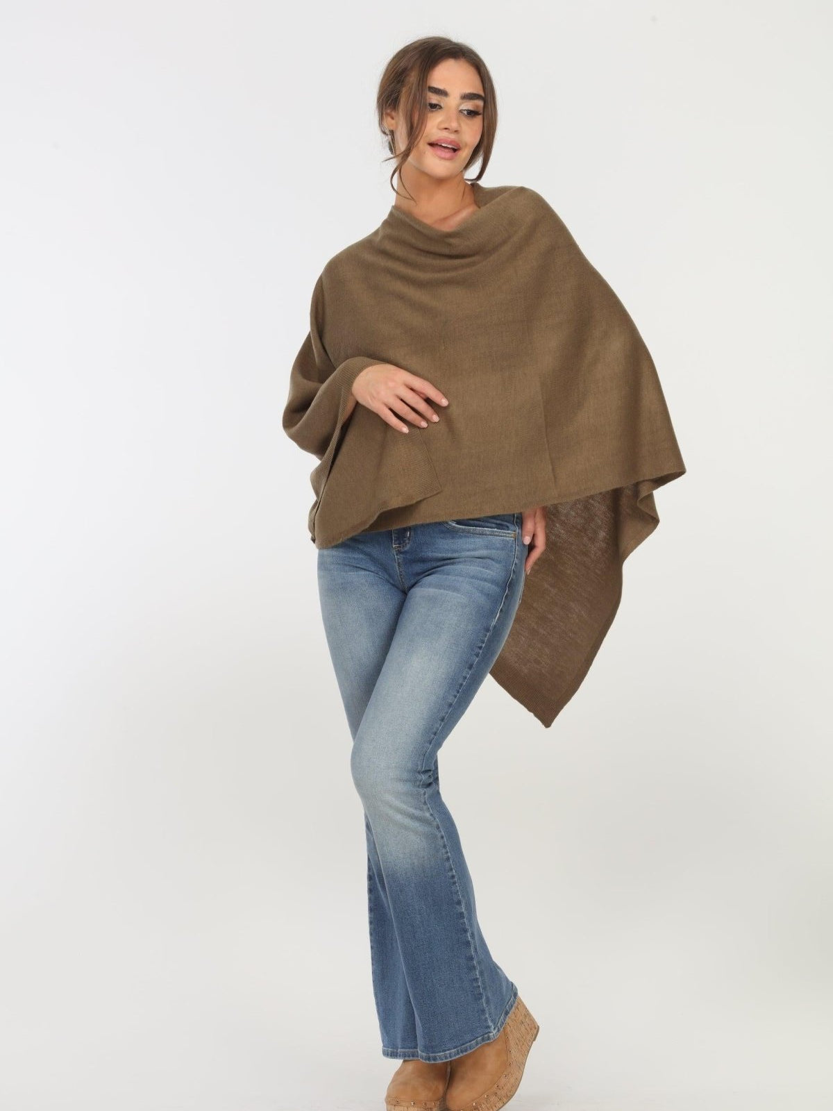 olive poncho on woman in denim pants and tan shoes