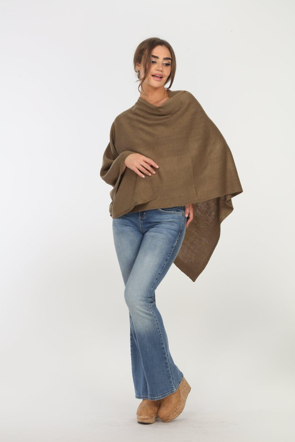 olive poncho on woman in denim pants and tan shoes