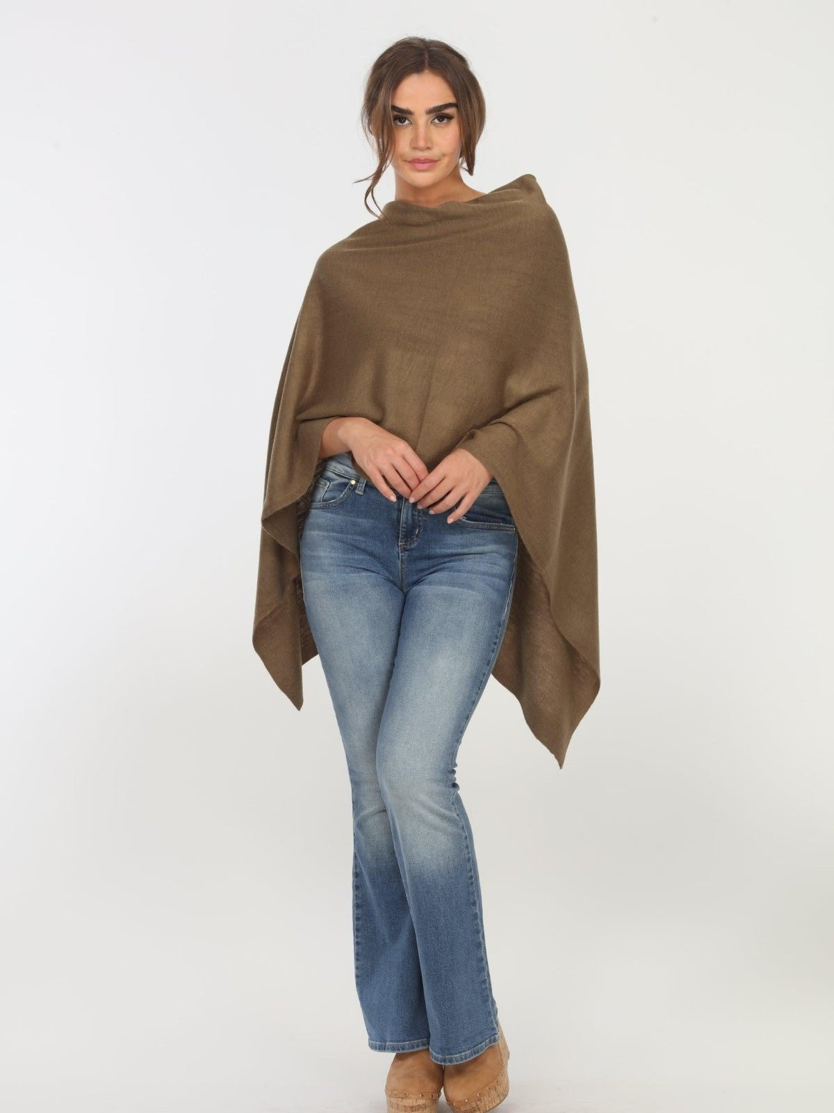 olive poncho on woman in denim pants and tan shoes