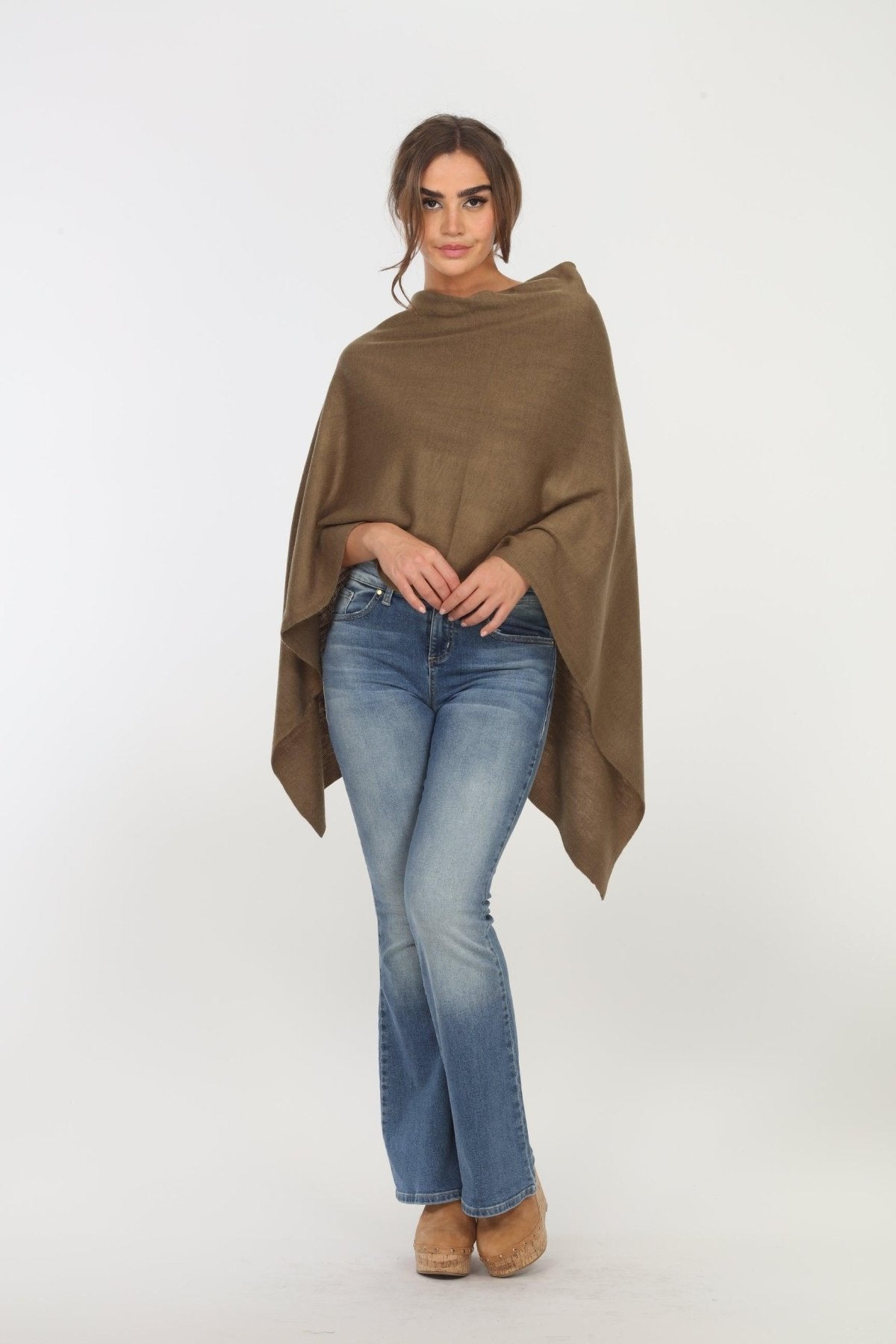 olive poncho on woman in denim pants and tan shoes