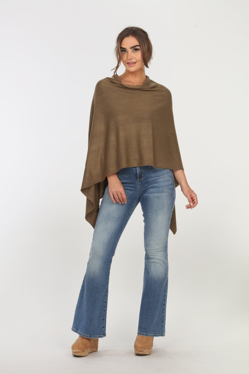 olive poncho on woman in denim pants and tan shoes