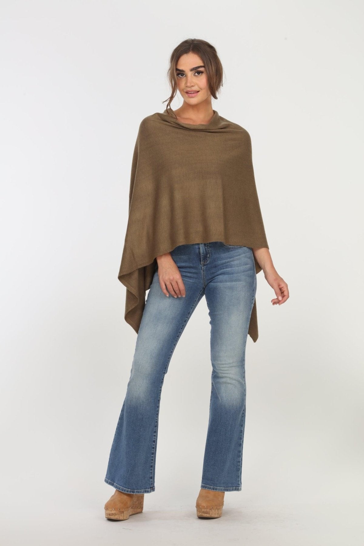olive poncho on woman in denim pants and tan shoes