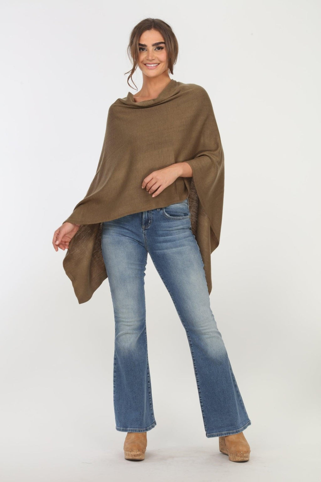 olive poncho on woman in denim pants and tan shoes