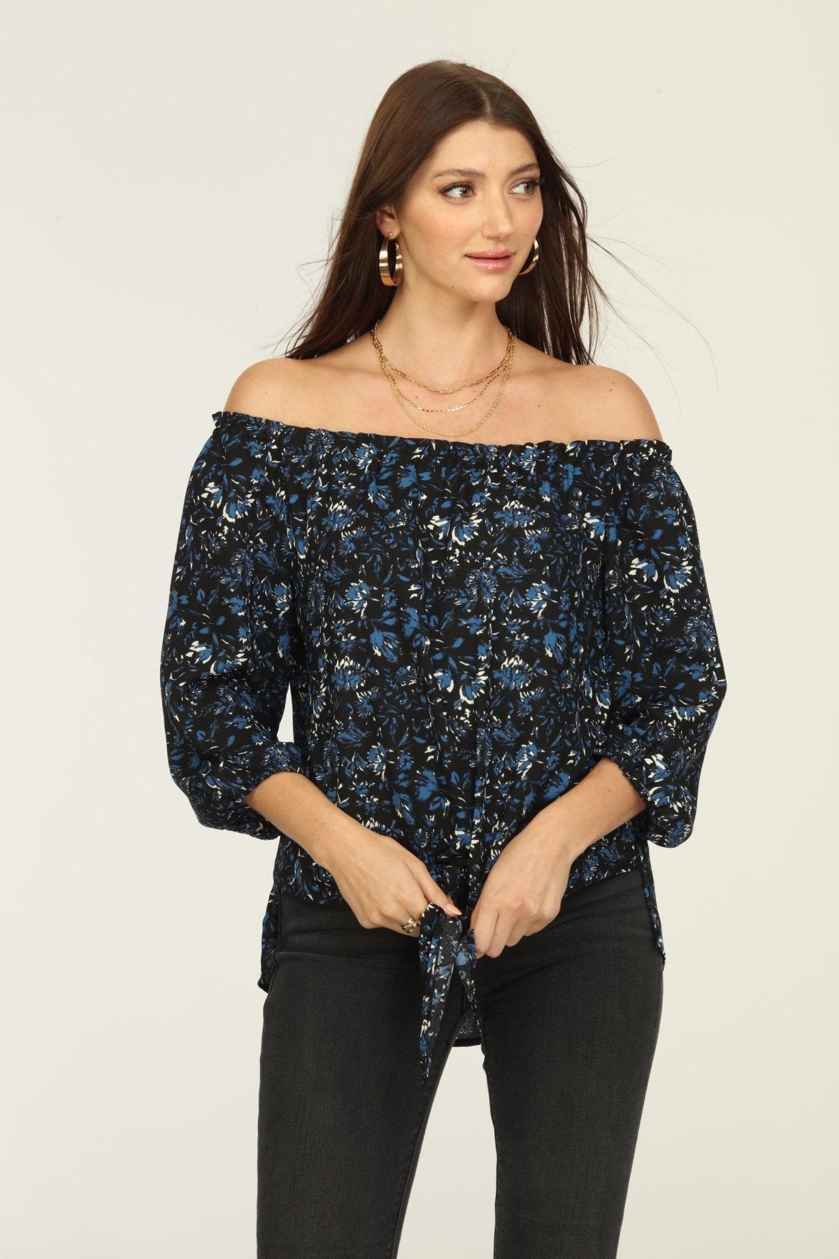 black and blue off the shoulder blouse on woman in dark denim pants