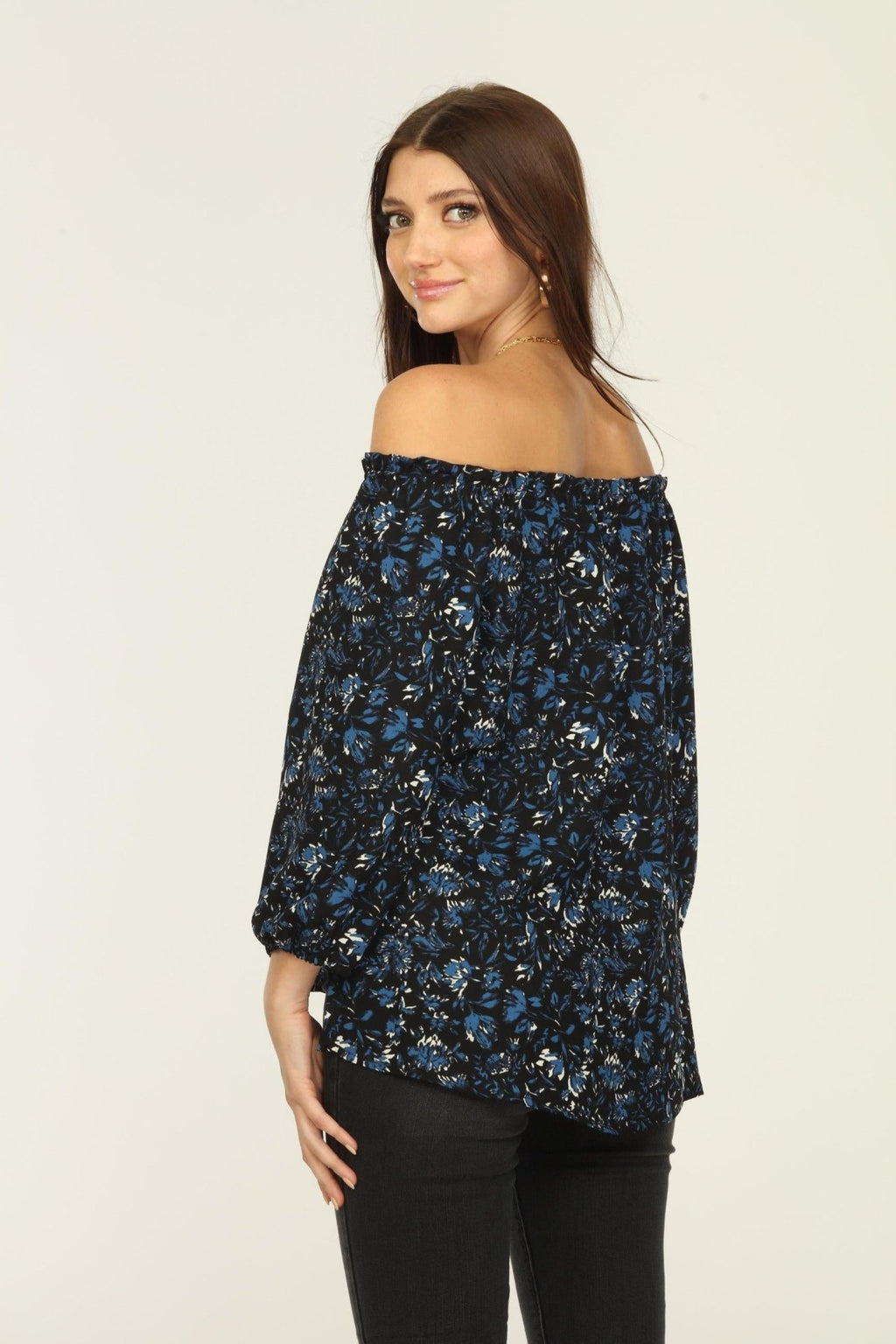 back side of black and blue off the shoulder blouse on woman in dark denim pants