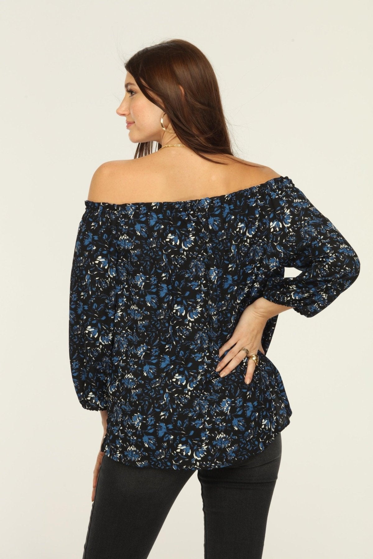 back side of black and blue off the shoulder blouse on woman in dark denim pants