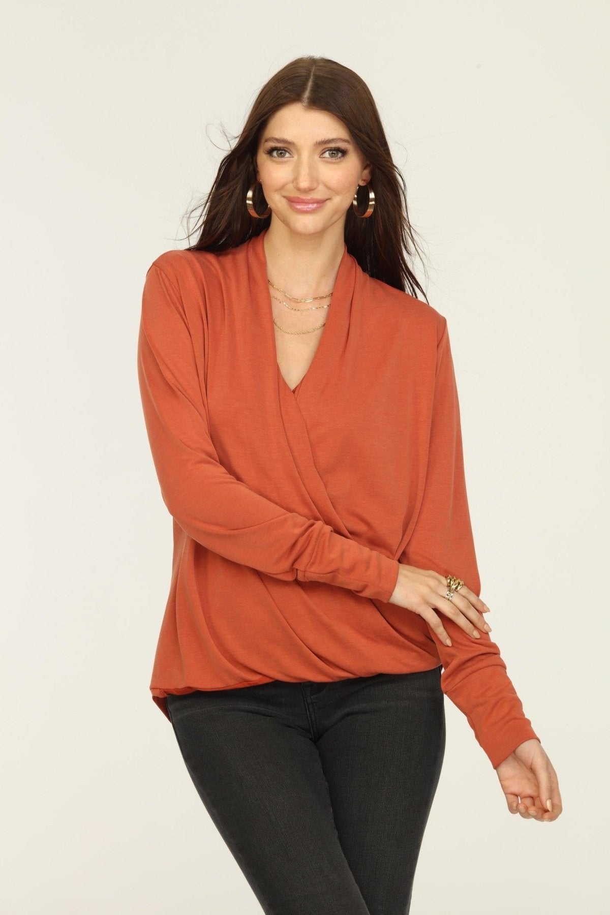 orange long sleeve draped top on woman in dark jeans