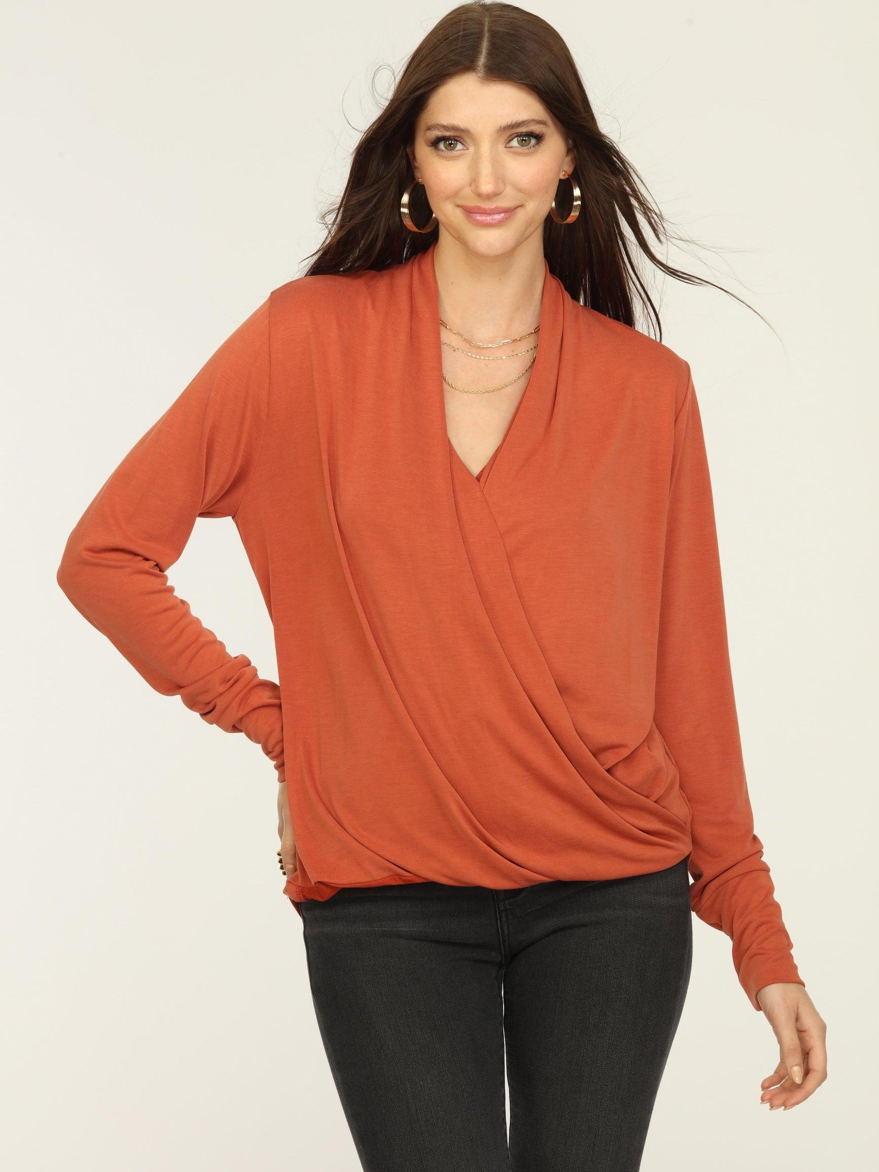 orange long sleeve draped top on woman in dark jeans