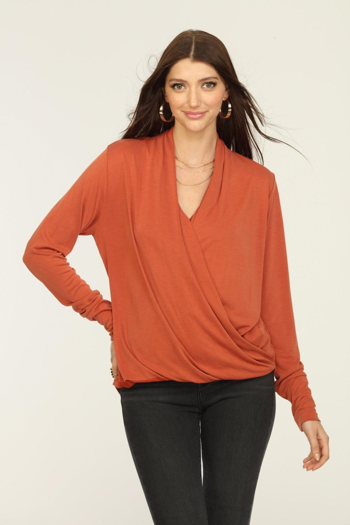 orange long sleeve draped top on woman in dark jeans