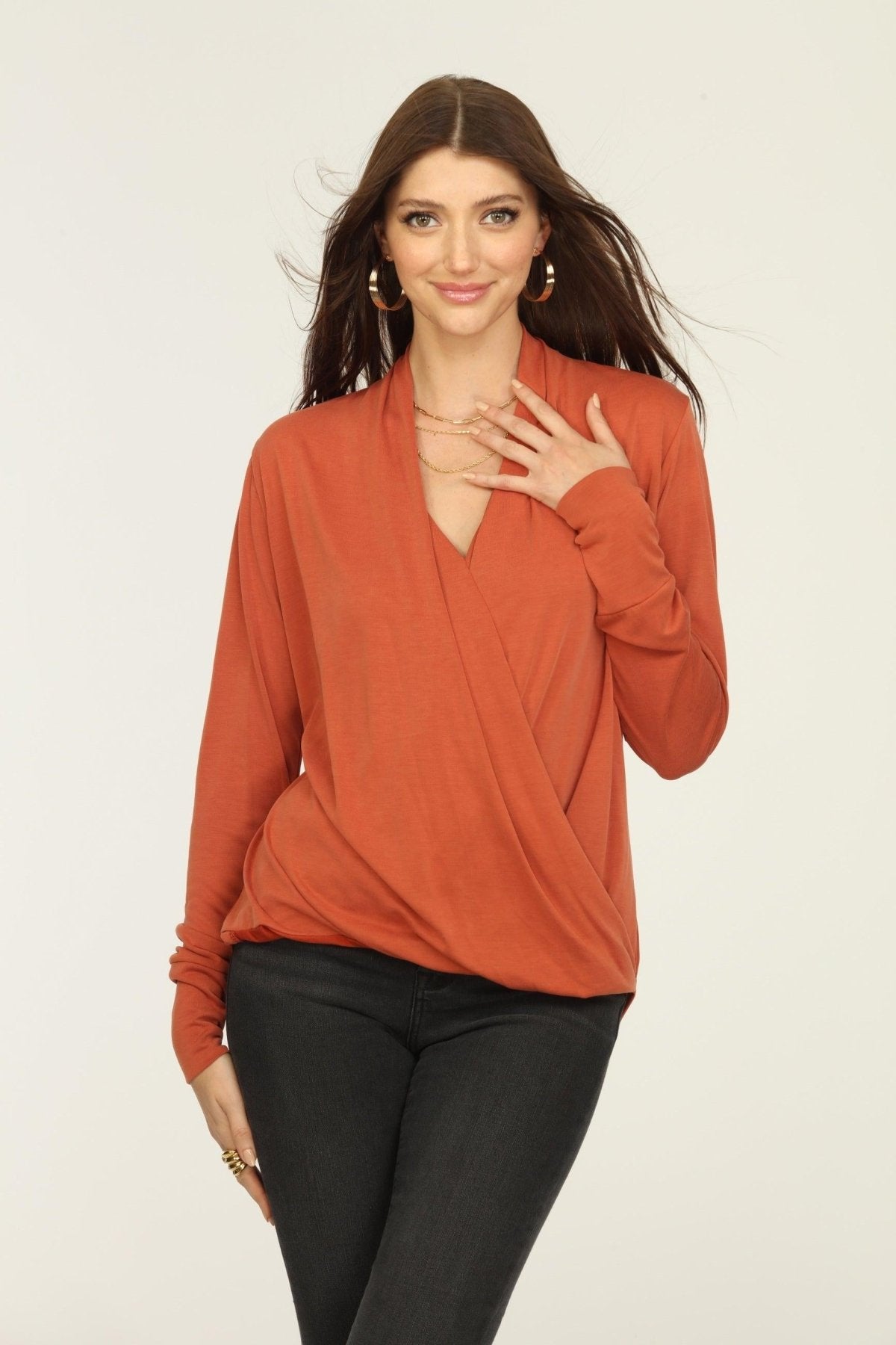 orange long sleeve draped top on woman in dark jeans