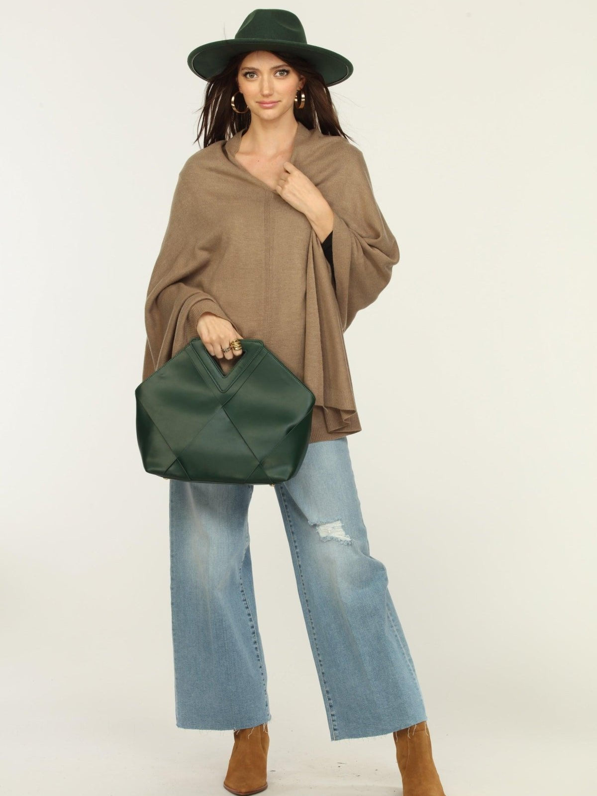 woman wearing a hat, tan poncho, jeans, and tan boots