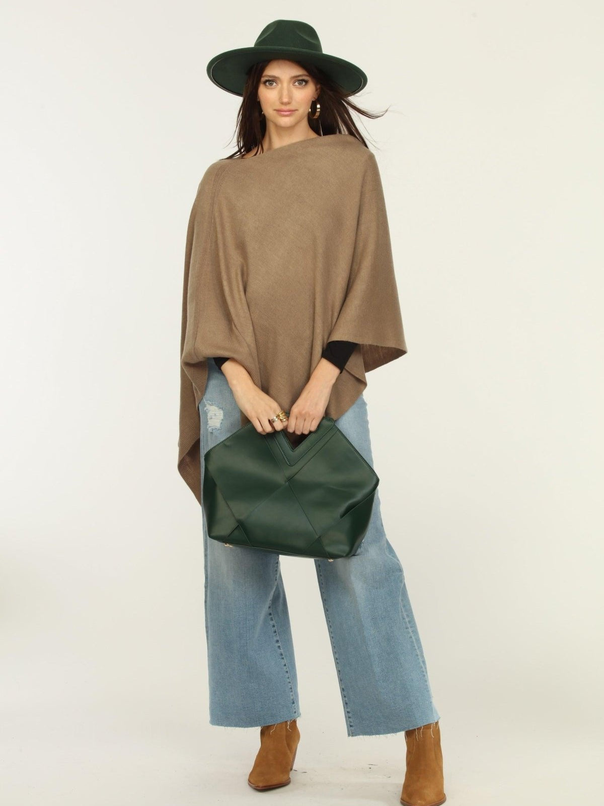 woman wearing a hat, tan poncho, jeans, and tan boots