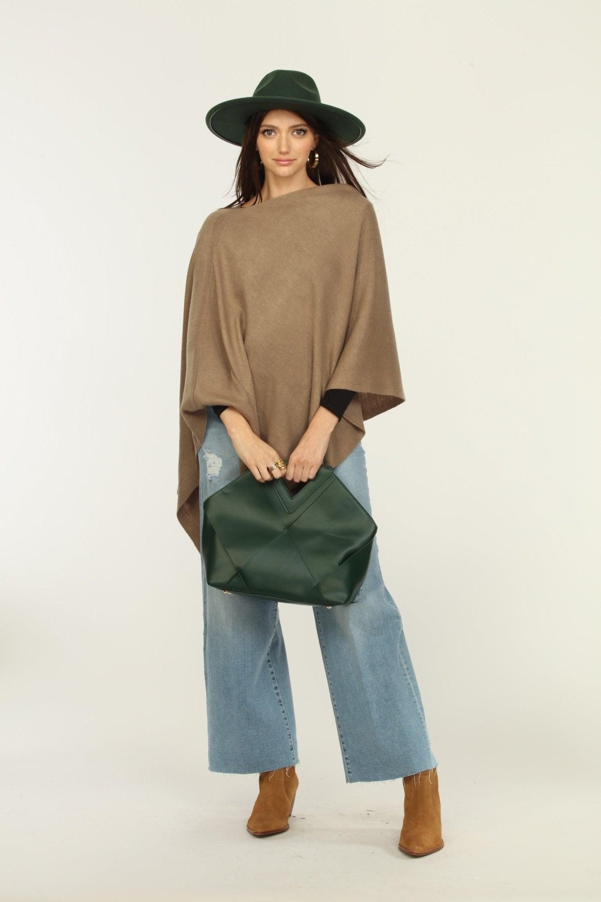 woman wearing a hat, tan poncho, jeans, and tan boots