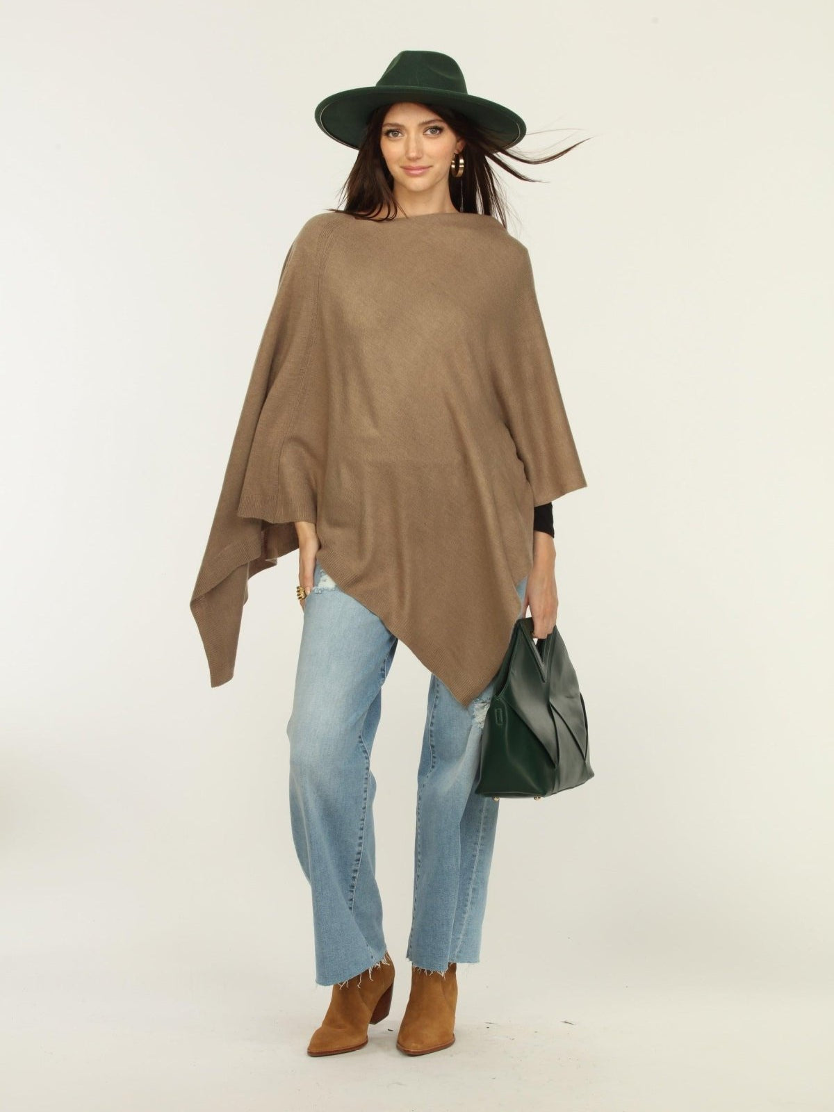 woman wearing a hat, tan poncho, jeans, and tan boots