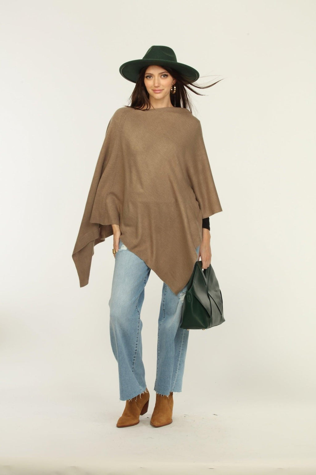 woman wearing a hat, tan poncho, jeans, and tan boots