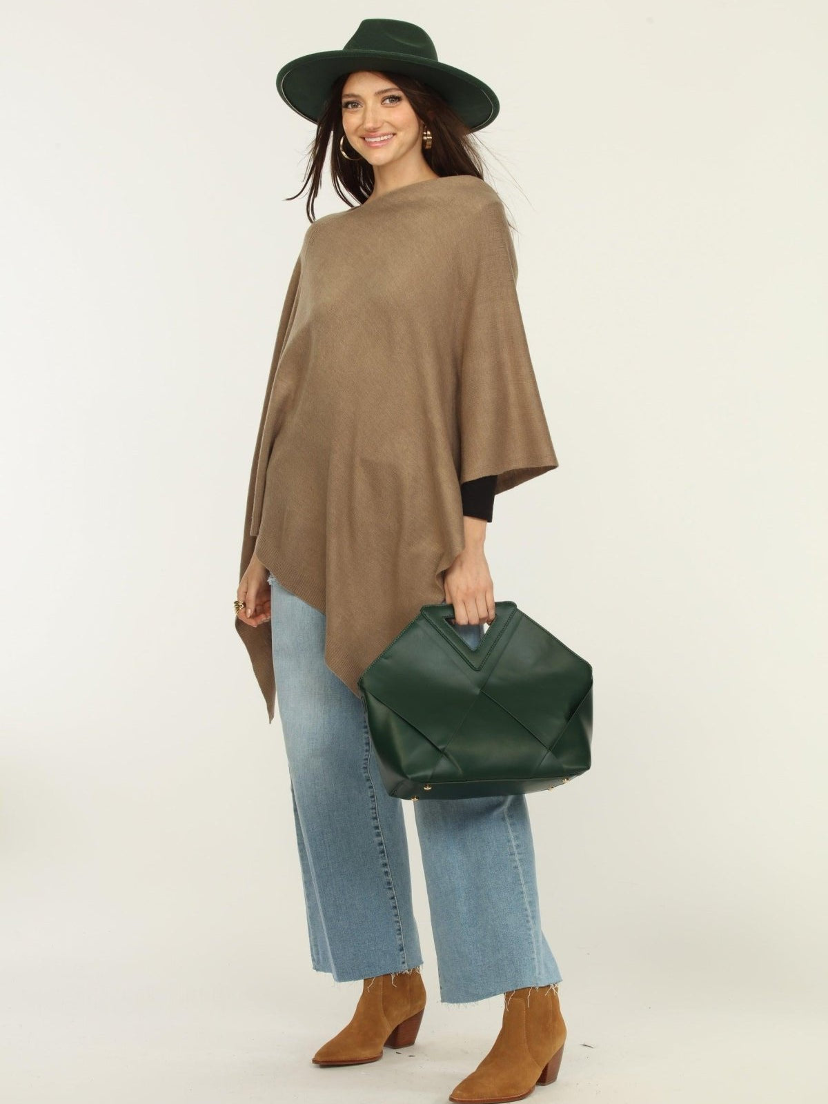 woman wearing a hat, tan poncho, jeans, and tan boots