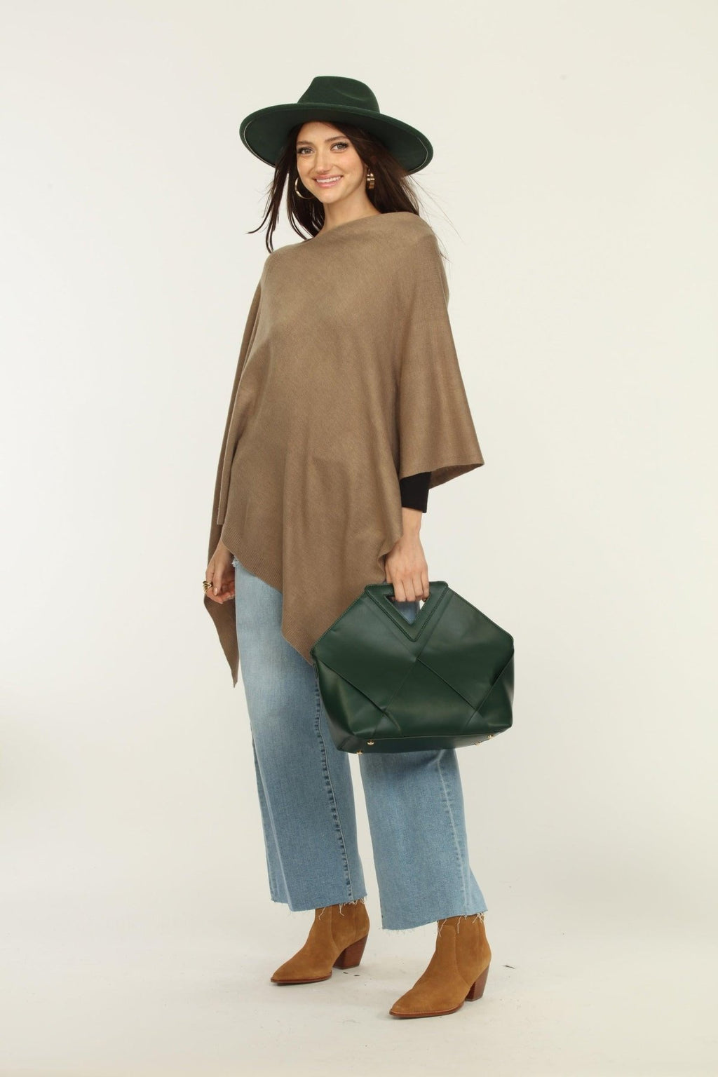 woman wearing a hat, tan poncho, jeans, and tan boots