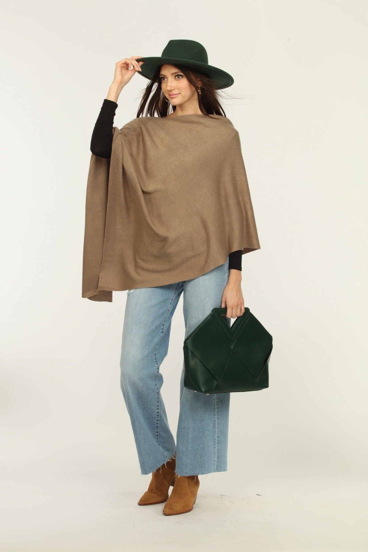 woman wearing a hat, tan poncho, jeans, and tan boots