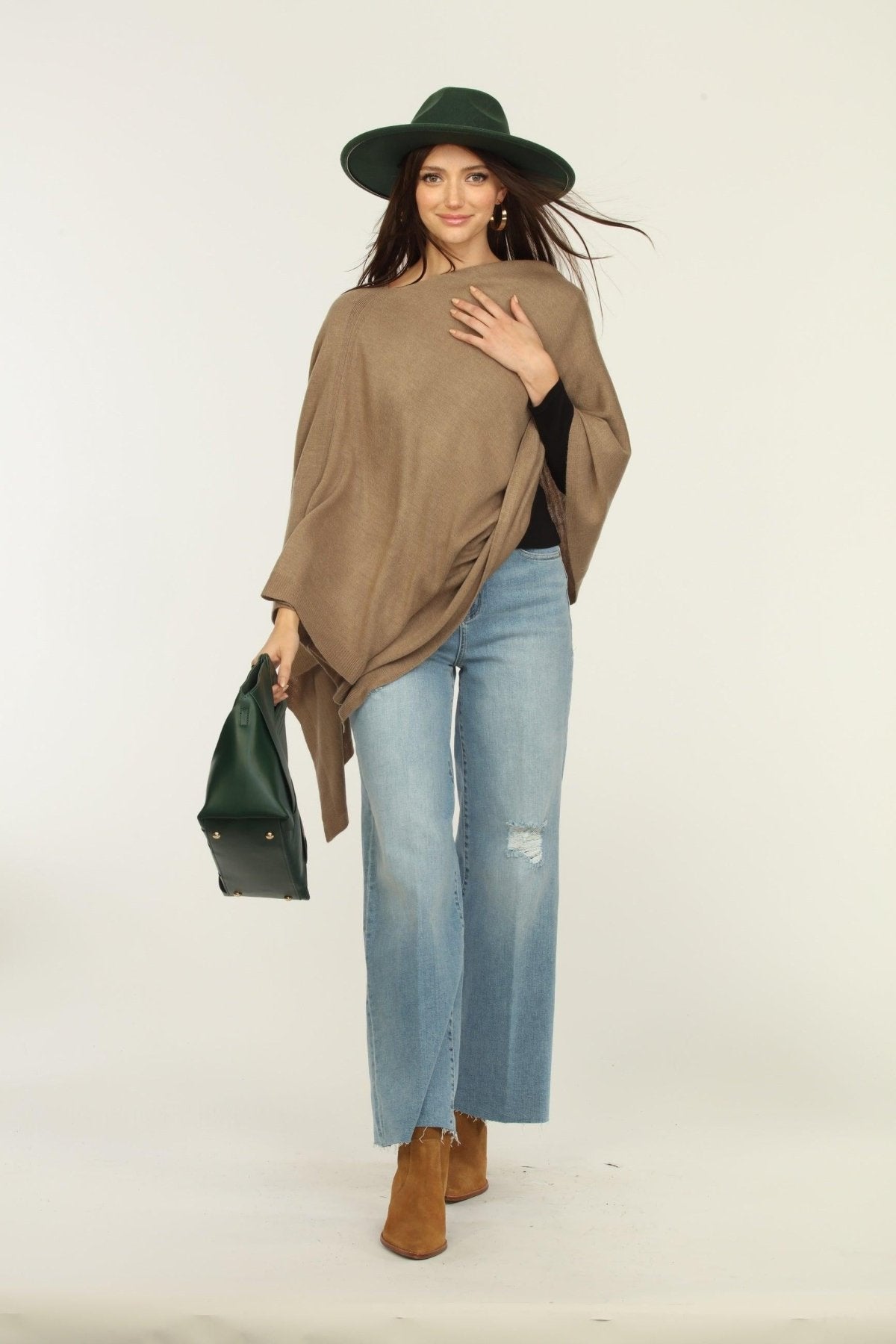 woman wearing a hat, tan poncho, jeans, and boots