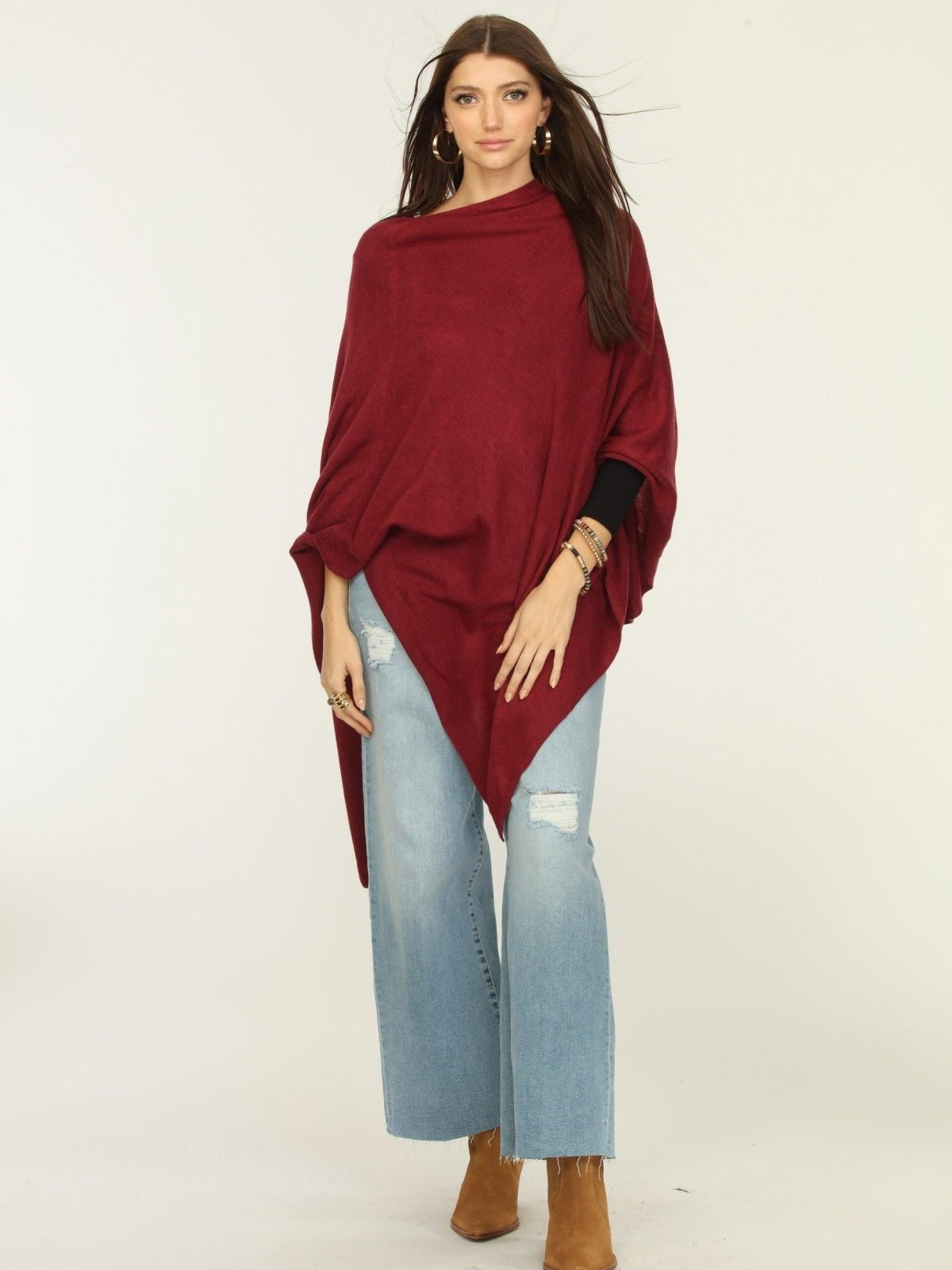 woman wearing burgundy poncho, jeans, and tan boots
